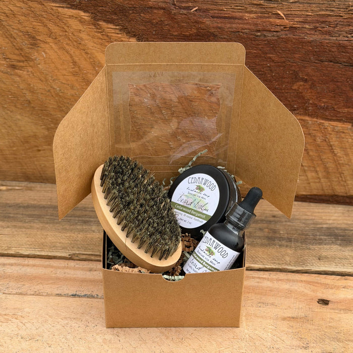 Beard oil, boar bristle brush and beard balm on wooden surface