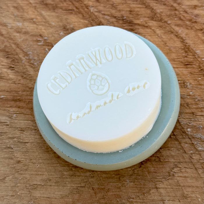 Round solid dish soap with concrete soap holder on wood surface