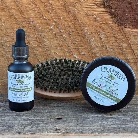 Beard oil, boar bristle brush and beard balm on wooden surface