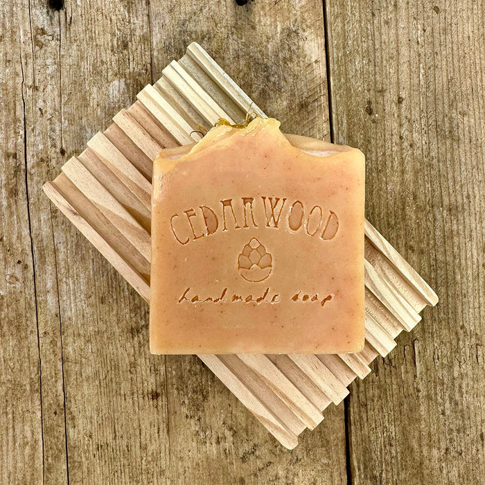 Orange marigold handmade soap bar on wood soap dish